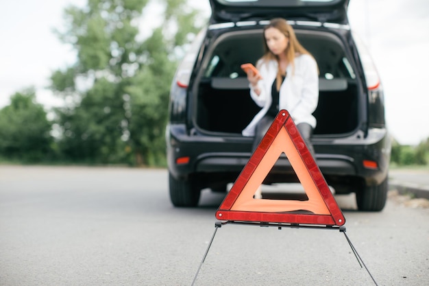 Mulher estressada procurando um carro quebrado e verificando o motor na estrada rural em vista lateral