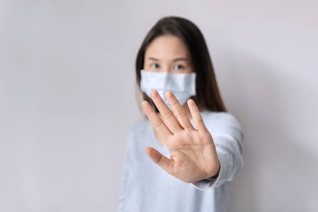 Mulher estressada usando máscara médica gesticulando para parar ou dizer não no fundo branco Copiar close up do espaço