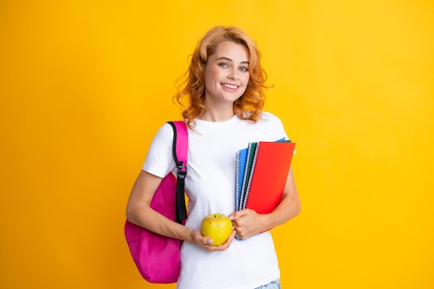 Mulher estudante bonita com mochila detém alguns documentos e livros sobre fundo amarelo