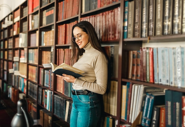 Mulher estudante em pé com livro aberto e prepare-se para exames na biblioteca