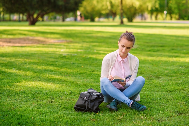 Mulher estudante está estudando ao ar livre no campus da universidade ao pôr do sol.