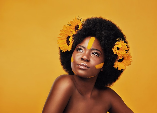 Mulher estúdio e pensar com foco e girassóis para planejamento de idéia ou visão com afro africana feminina e pensou em pano de fundo de mostarda com maquiagem beleza natural ou cuidados com a pele com sustentabilidade