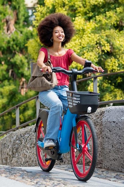 Mulher étnica encantada andando de bicicleta na rua no verão