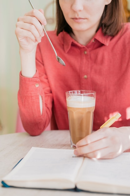 Mulher europeia bebe café em uma xícara doente em uma cafeteria, mulher branca bebe um latte ou cappuccino em um restaurante no café da manhã ou almoço, desfrute do sabor do café e socialize com os amigos