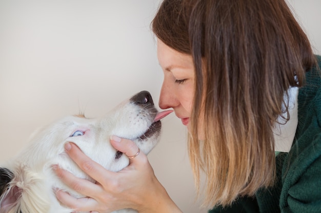 Mulher europeia com jaqueta verde beijando pastor australiano