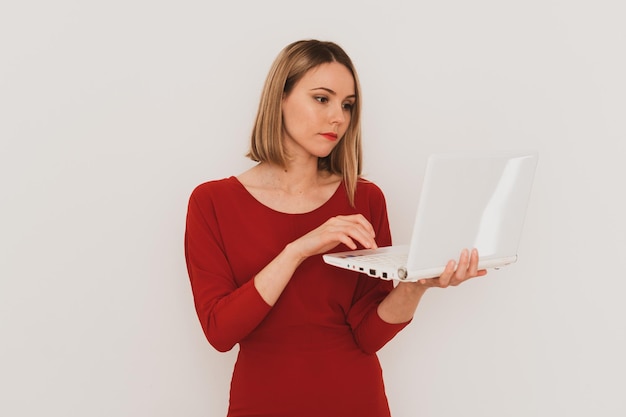 Mulher europeia elegante em vestido vermelho usando laptop para comunicação isolada no fundo branco