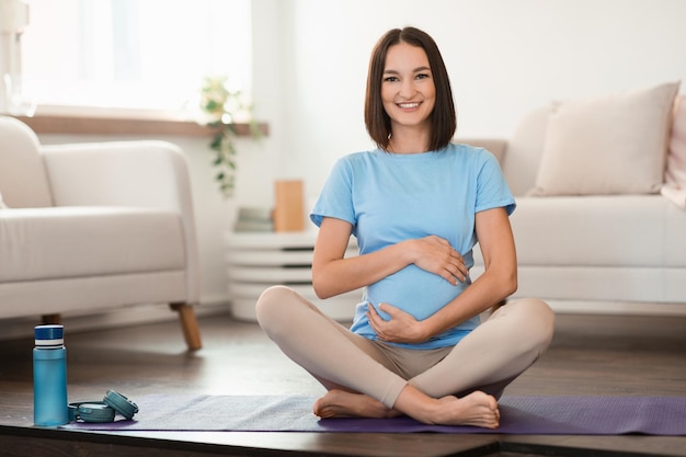 Mulher europeia grávida a fazer ioga matinal em casa