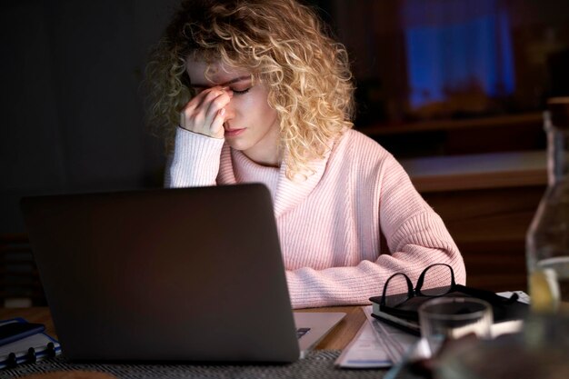 Mulher exausta trabalhando em um laptop em casa