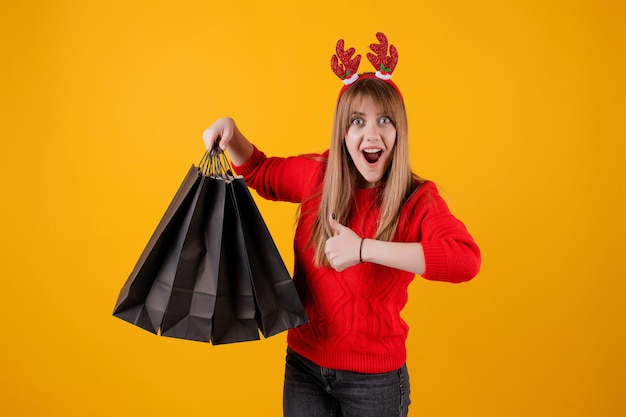 Mulher excitada com presentes em sacolas de compras usando aro engraçado