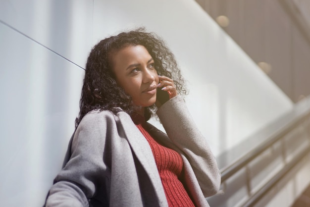 Mulher excitada com um smartphone em pé nos degraus do metrô