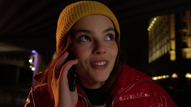Mulher excitada falando celular na cidade noturna garota usando telefone na rua