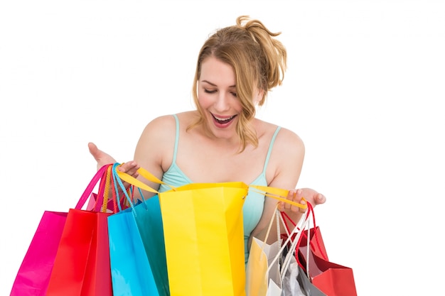 Mulher excitada olhando muitas sacolas de compras