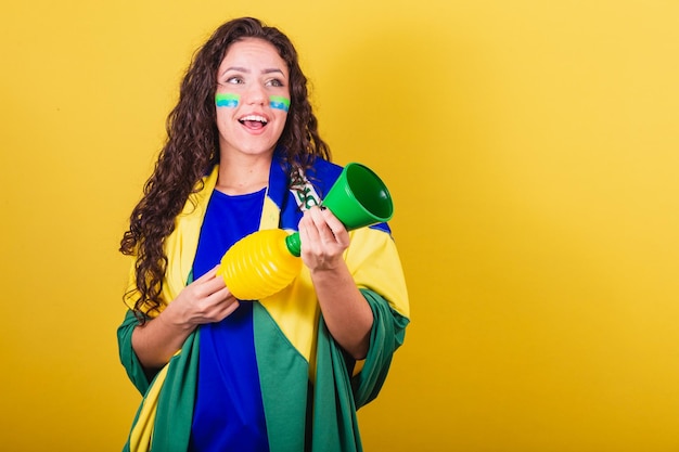 Mulher fã de futebol da copa do mundo do brasil segurando instrumento de som de chifre fazendo barulho ao torcer