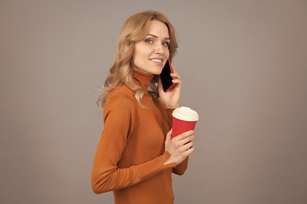 Mulher fala no telefone segurando a xícara Comunicação móvel Café ou café expresso a qualquer hora em qualquer lugar