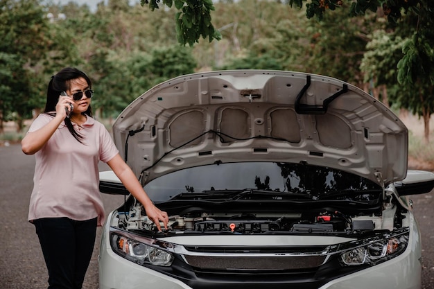 Foto mulher falando ao telefone enquanto estava de pé perto de um carro de avaria