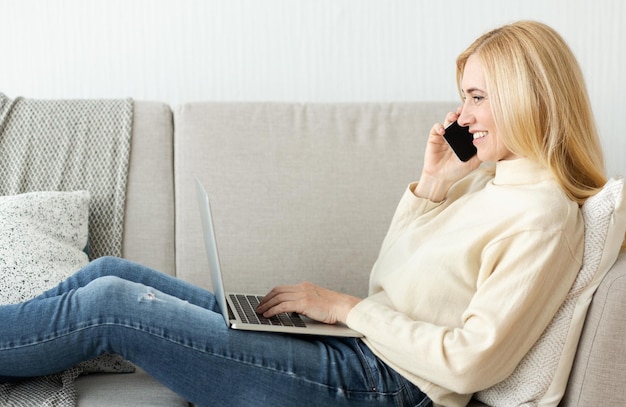 Mulher falando ao telefone usando o computador portátil