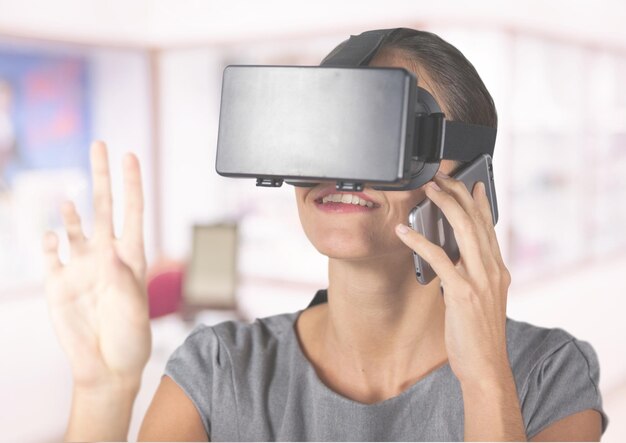 Mulher falando no celular enquanto usa fone de ouvido de realidade virtual