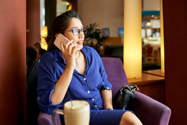 Mulher falando no celular no café