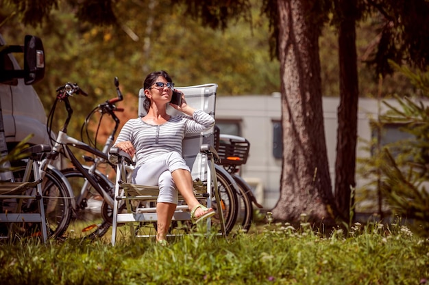 Mulher falando no telefone inteligente ao ar livre em um acampamento para turistas. Férias de carro de caravana. Viagem de férias em família, viagem de férias em motorhome RV. Tecnologia de comunicação de informação de conexão.