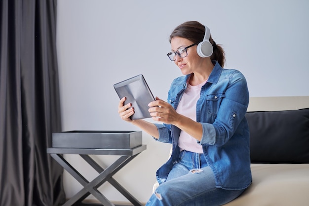 Mulher falante em fones de ouvido olhando para webcam de tablet digital