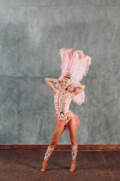 Mulher fantasiada de samba ou lambada com plumagem de plumas rosa.