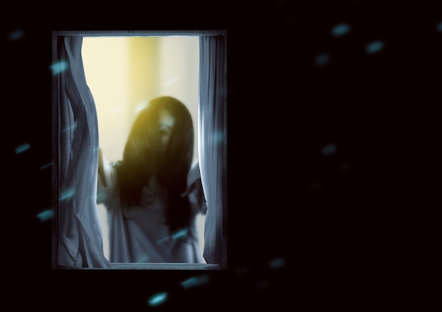 Mulher fantasma assustadora em pé na janela. Conceito de halloween