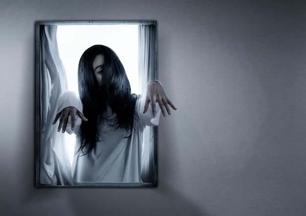 Mulher fantasma assustadora em pé na janela da casa abandonada. Conceito de halloween