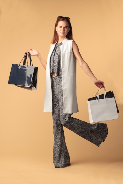 Mulher fashionista feliz com sacolas isoladas em fundo bege