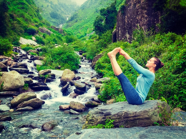 mulher faz asana de equilíbrio de ioga Ubhaya padangusthasana Big Double Toe Yoga Pose em cachoeira tropical