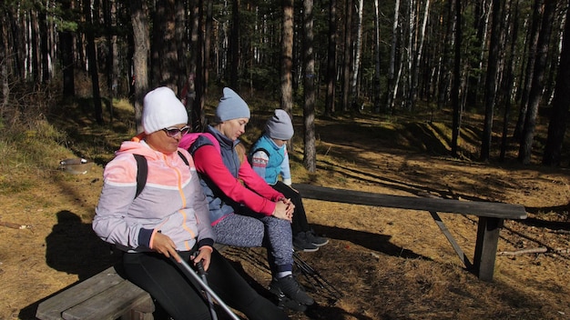 Mulher faz caminhada nórdica na natureza Meninas e crianças usam bastões de trekking e mochilas de pólos nórdicos Família viaja e pratica esportes Floresta de outono