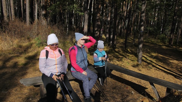 Mulher faz caminhada nórdica na natureza meninas e crianças usam bastões de trekking e mochilas de pólos nórdicos