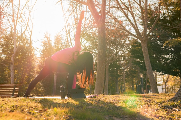 Mulher faz exercícios de ioga em um parque ao pôr do sol