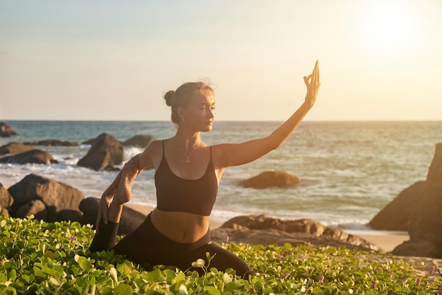 Mulher faz ioga asana para estilo de vida saudável na costa do mar tropical ou praia oceânica ao ar livre no pôr do sol