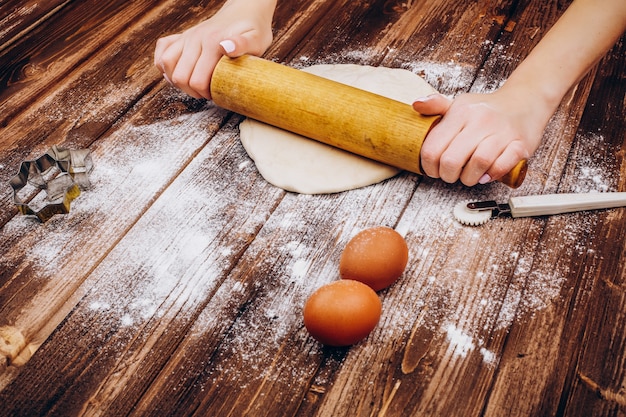 Mulher faz pastelaria de Natal na massa na mesa de madeira