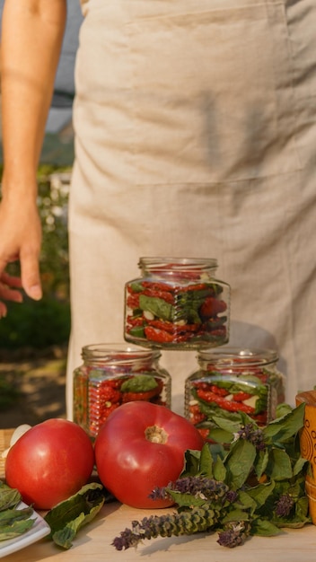 mulher faz preparativos para tomates secos de inverno, alho picado e manjericão fresco