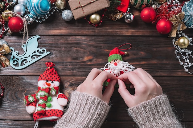 Mulher faz presentes de Natal em uma mesa de madeira escura.