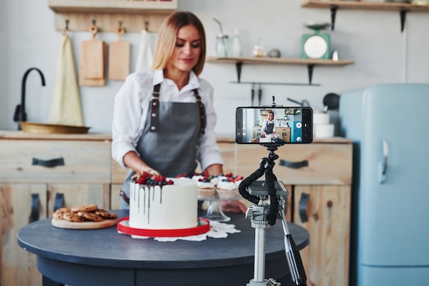 Mulher faz tortas e doces deliciosos. Processo de gravação por smartphone no tripé.