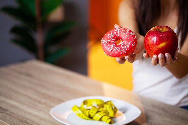 Mulher faz uma escolha entre alimentos prejudiciais e saudáveis