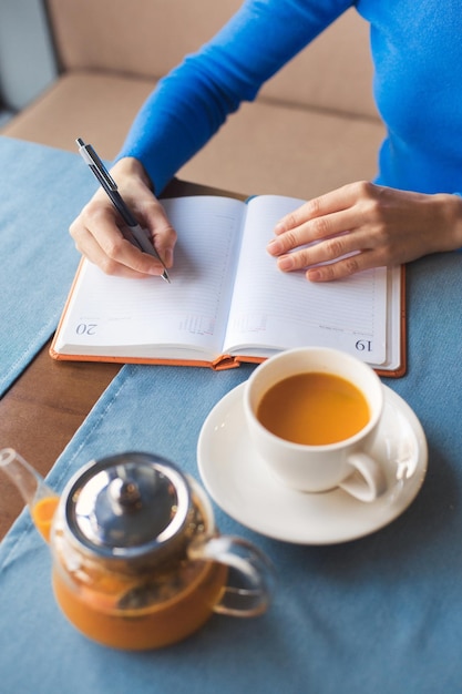 Mulher faz uma pausa para o chá durante o horário de trabalho e planeja o próximo dia de trabalho no notebook