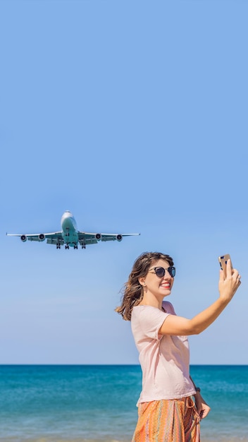 Mulher faz uma selfie na praia observando os aviões de pouso viajando em um texto de conceito de avião