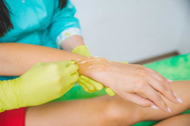 Mulher fazendo açúcar no centro cosmético depilação beleza mãos fecham