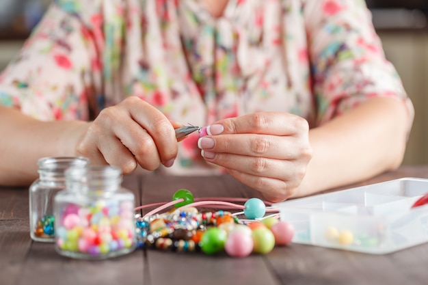Mulher fazendo bijuteria de arte de artesanato em casa