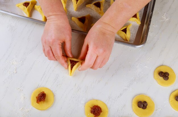 Mulher fazendo biscoito triangular para férias judaicas Purim.
