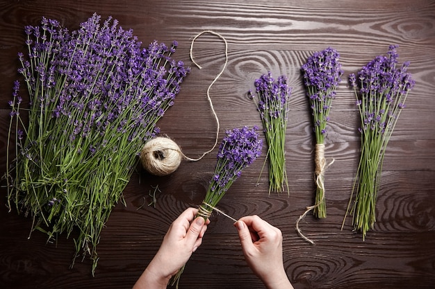 Mulher fazendo buquês de lavanda em madeira escura