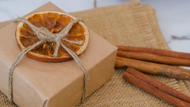 Mulher fazendo caixa com presentes de ano novo embrulhados em papel artesanal e decorados com fatias de laranja seca Conceito de feriados e presentes Artesanal Ecologicamente correto alternativo verde Presentes de Natal sem desperdício