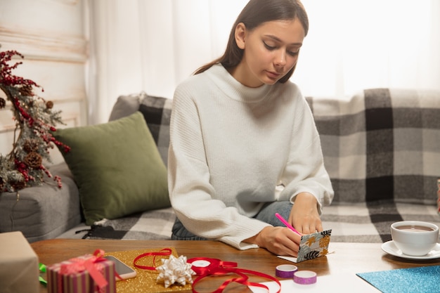 Mulher fazendo cartões de felicitações para o Ano Novo e o Natal de 2021 para amigos ou recados de família