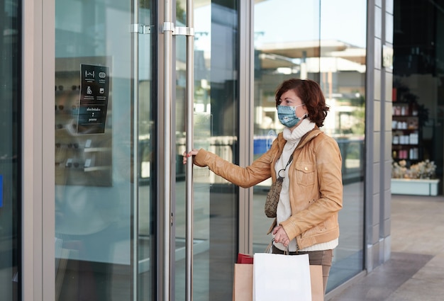 Mulher fazendo compras em um shopping com máscara facial, novo normal, covid-19