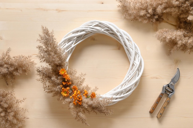 Mulher fazendo coroa com flores de laranja e materiais naturais secos