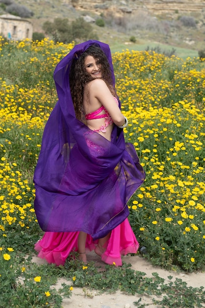 Mulher fazendo dança oriental do ventre vestindo traje colorido dançando ao ar livre