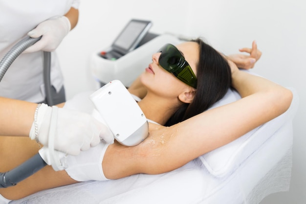 Mulher fazendo depilação a laser nas axilas em salão de depilação